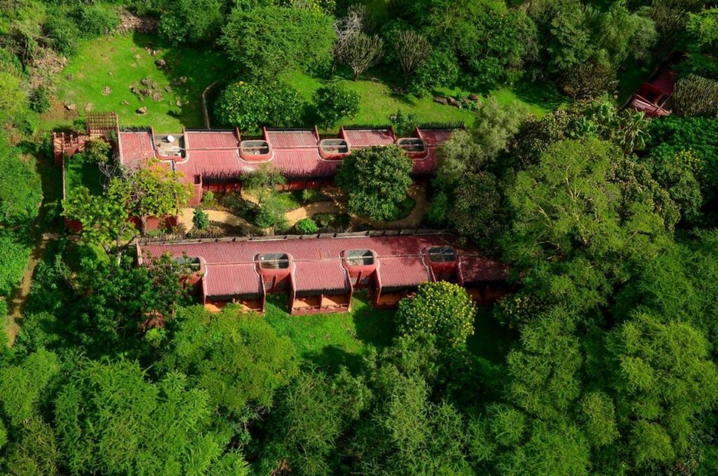 Dwa skrzydła Amboseli Serena Safari Lodge z czerwonymi dachami widziane z lotu ptaka, wśród drzew