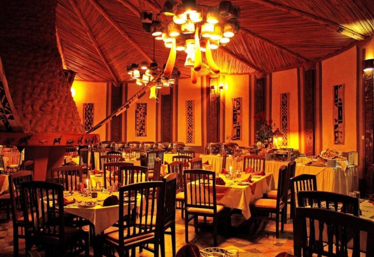 Sala restauracyjna wieczorem, ze stołami nakrytymi żółtymi obrusami i zapalonymi żyrandolami