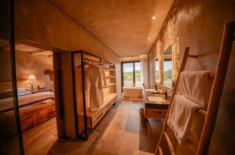 Przejście do łazienki w apartamencie, z szafą, podwójną umywalką i wanną