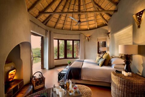 Apartament Madikwe Safari Lodge pod dachem krytym strzechą, z dużym łóżkiem i płonącym kominkiem