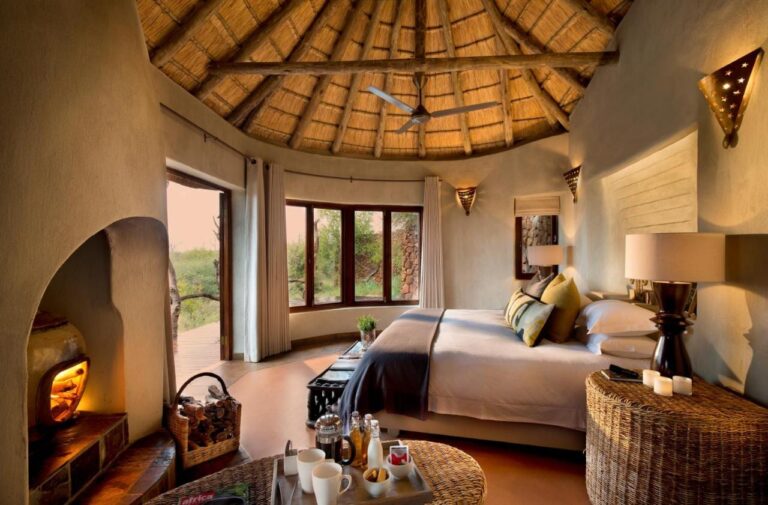 Apartament Madikwe Safari Lodge pod dachem krytym strzechą, z dużym łóżkiem i płonącym kominkiem