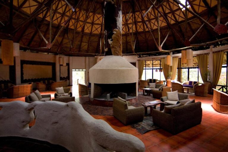 Salon pod okrągłą drewnianą więźbą, z fotelami wokół białego kominka