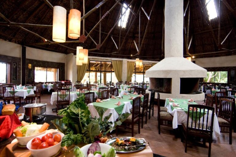 Restauracja ze stołami nakrytymi zielonymi obrusami i bufetem z warzywami na pierwszym planie