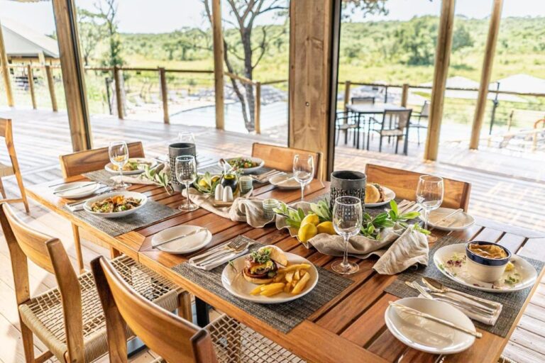 Nakryty stół w restauracji otwartej na taras, basen i busz