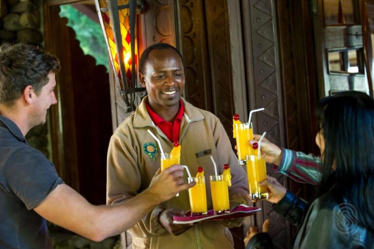 Pracownik Ngorongoro Serena Safari Lodge podaje dwojgu podróżnym tacę z sokami owocowymi