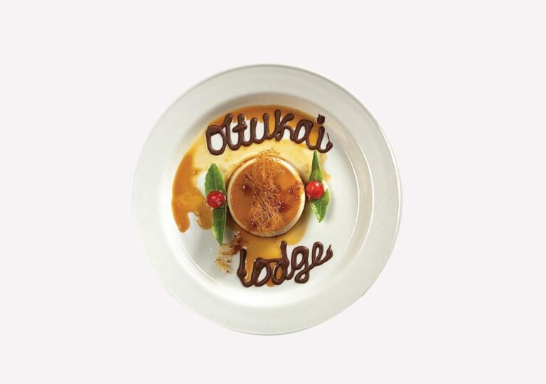 Flan karmelowy z napisem Ol Tukai Lodge z czekolady na talerzu