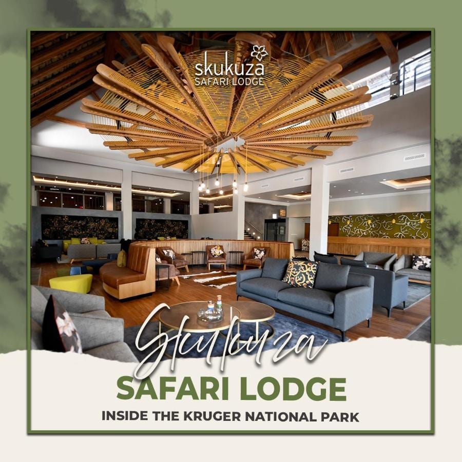 Salon w holu Skukuza Safari Lodge pod sufitem z drewnianych listew ułożonych w gwiazdę, z nałożoną nazwą obiektu